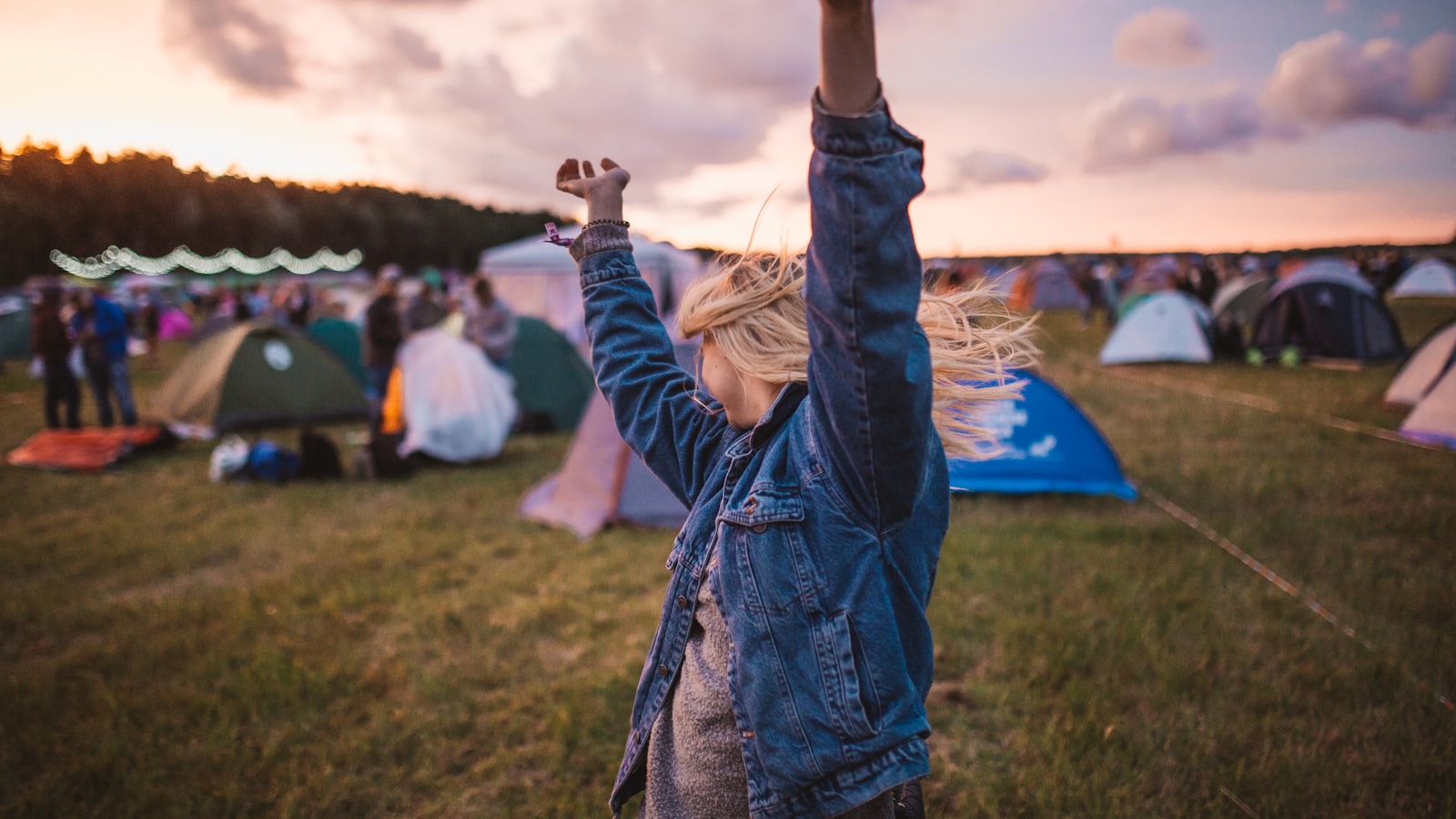 Festival camping area at sunrise, with tents and attendees waking up