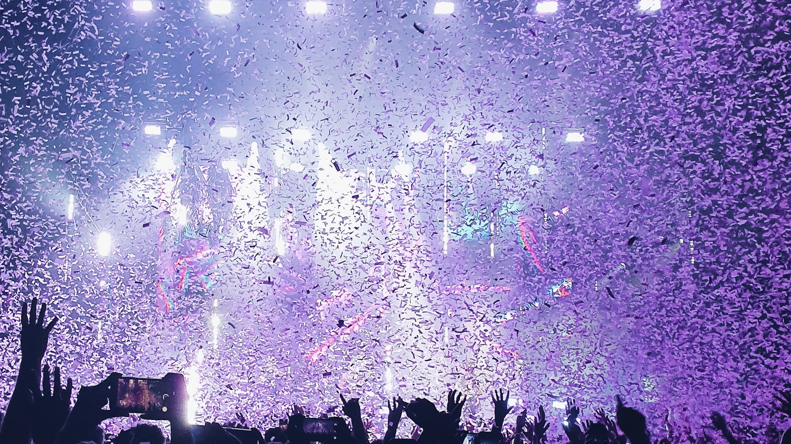Confetti falling over the crowd during a lit concert