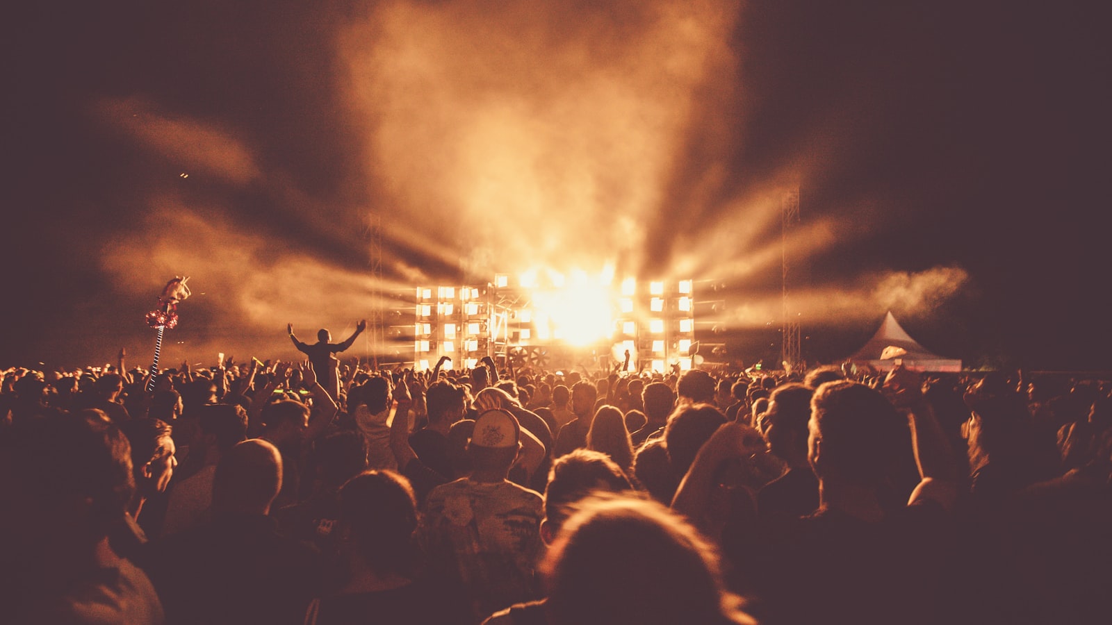 Stage lights pointing in different directions over a concert crowd